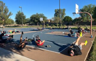 A group of people sitting on top of a basketball court.