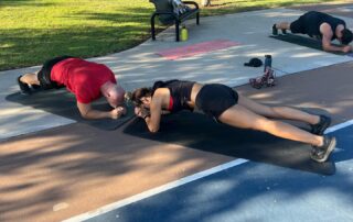 A man and woman doing yoga on the ground.