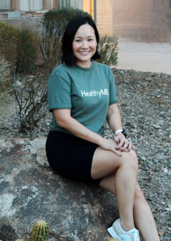 Woman in "Healthy ME" shirt smiling.