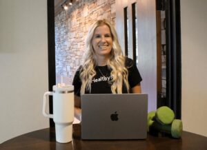 A woman sitting at a table with an apple laptop.